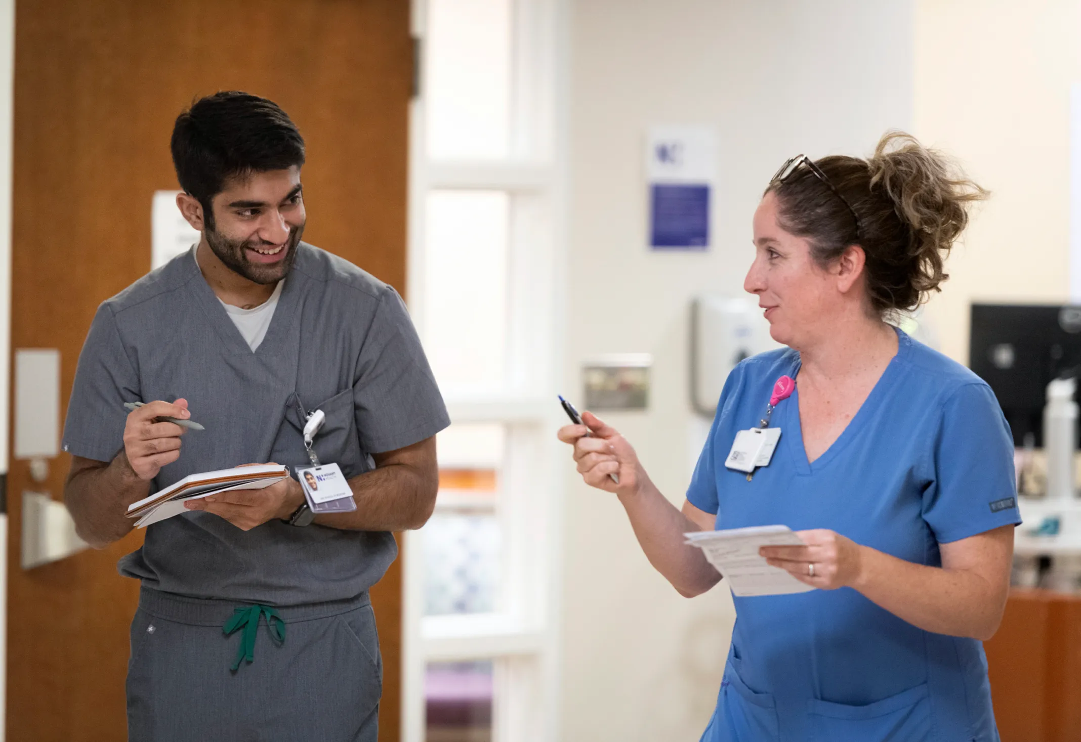 2 Novant Health providers smiling as they walk and work on paperwork