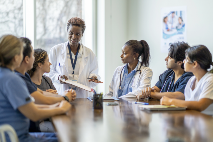 A group of providers seated around a table attentively listen to the speaker