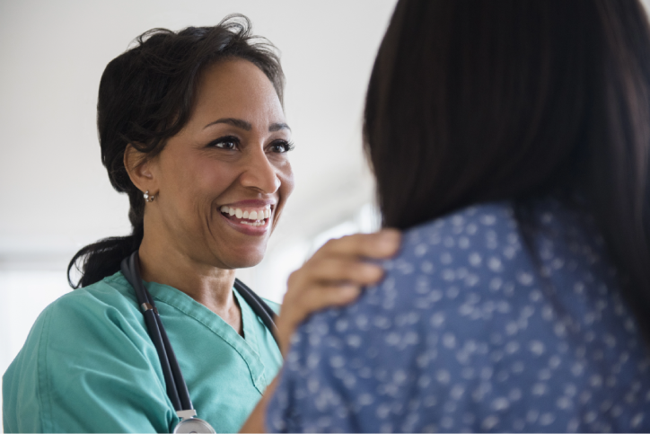A smiling provider puts a reassuring hand on her patient’s shoulder