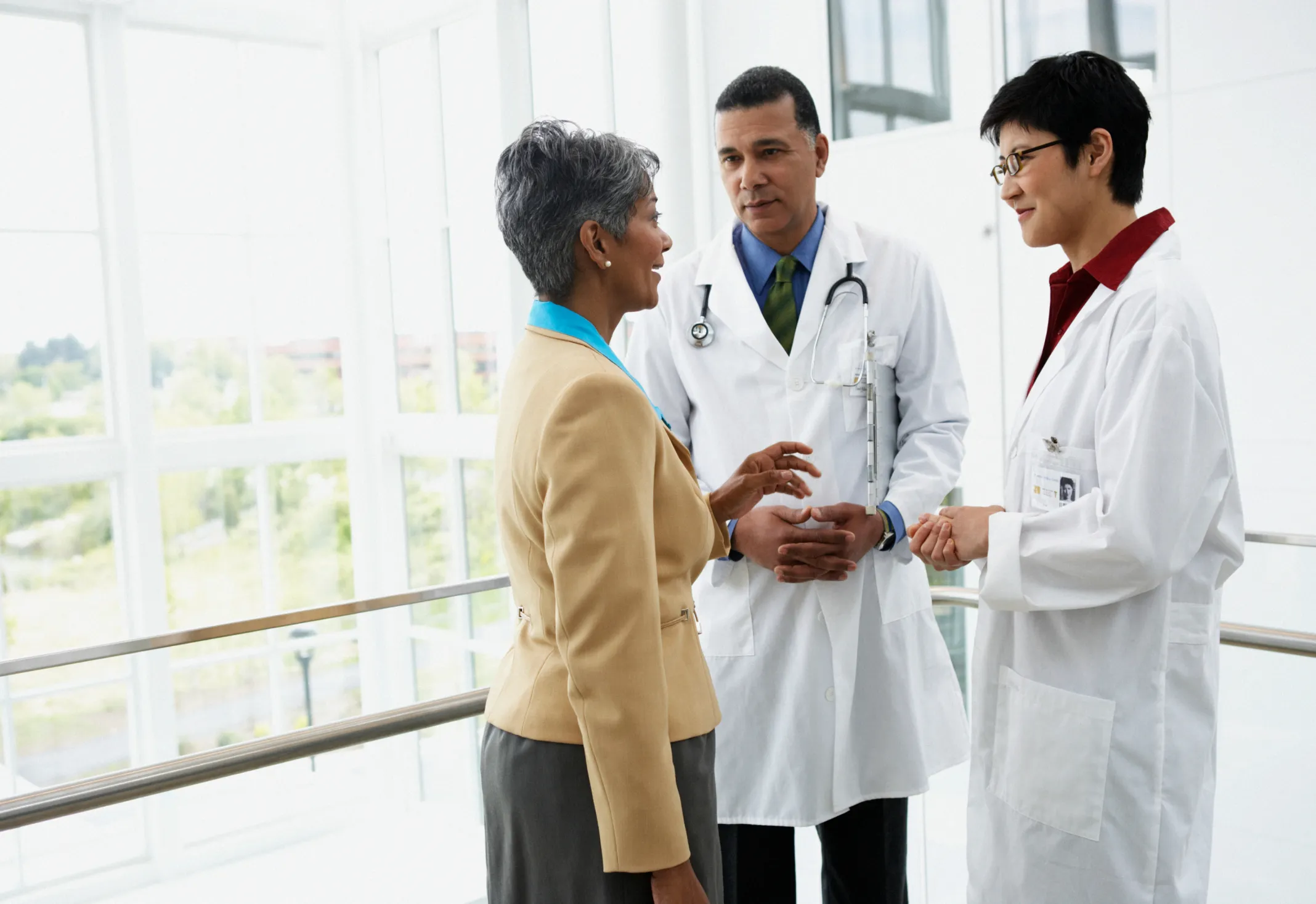 Two doctors attentively listen to a patient