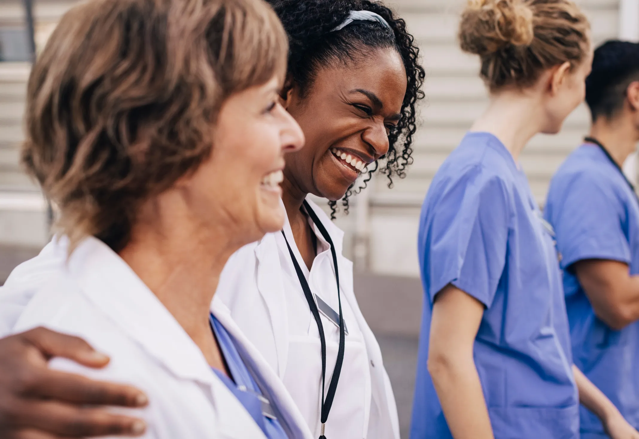 Two doctors smiling and laughing as they walk with a crowd