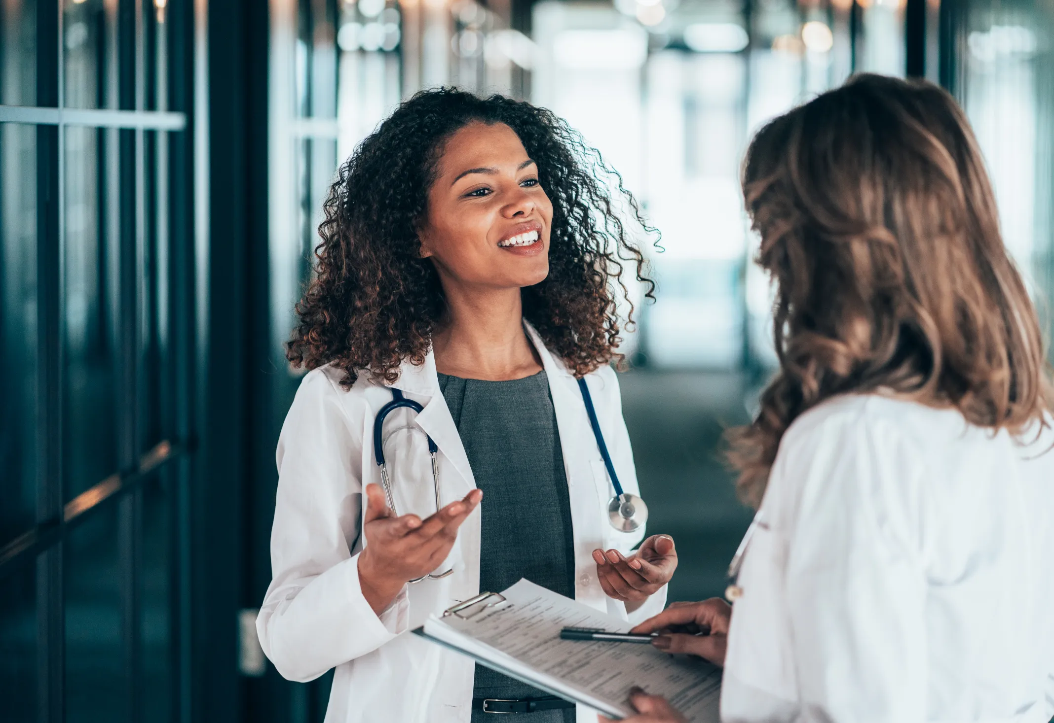 A provider with curly hair reassuringly talks to a patient