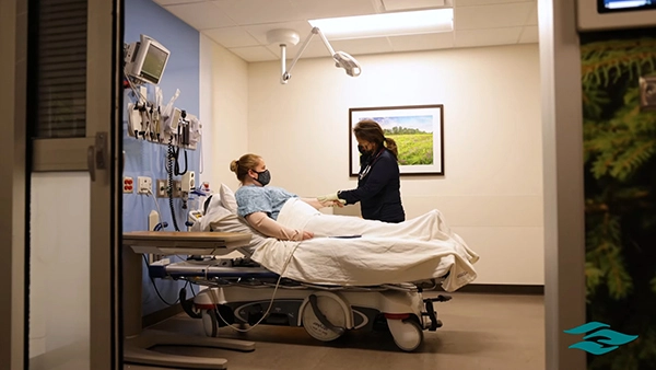 Nurse checking on a patient in a Riverside hospital room, reflecting our culture of compassion and change.