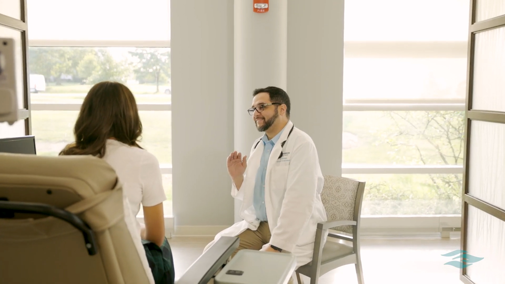 Dr. Hamdan, a Riverside Medical Group oncologist, speaking with a patient in a bright exam room.