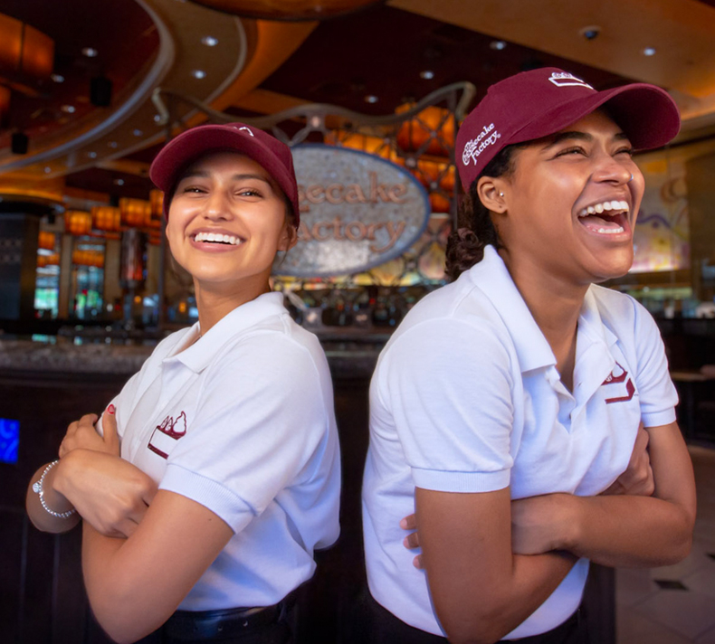 Smiling female server holding two large plates of food.