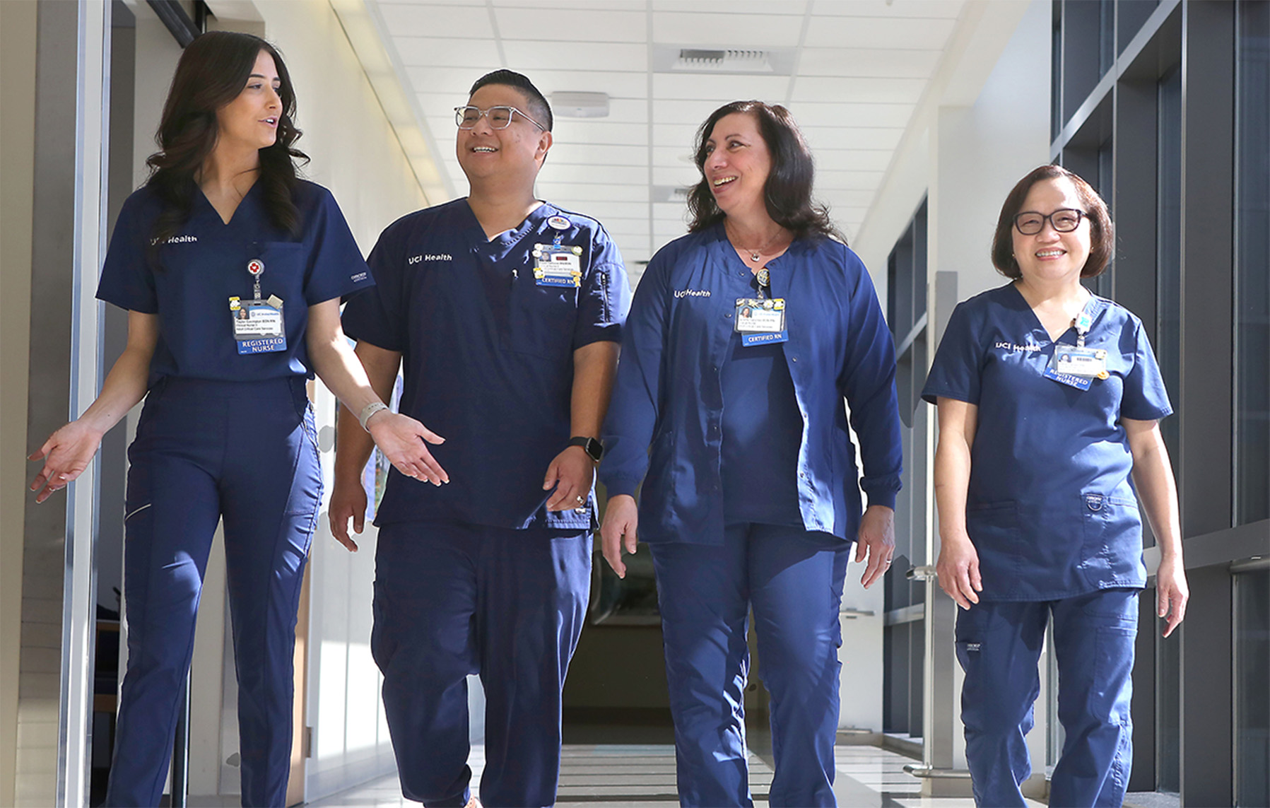 Three female and a male nurses smiling and talking.