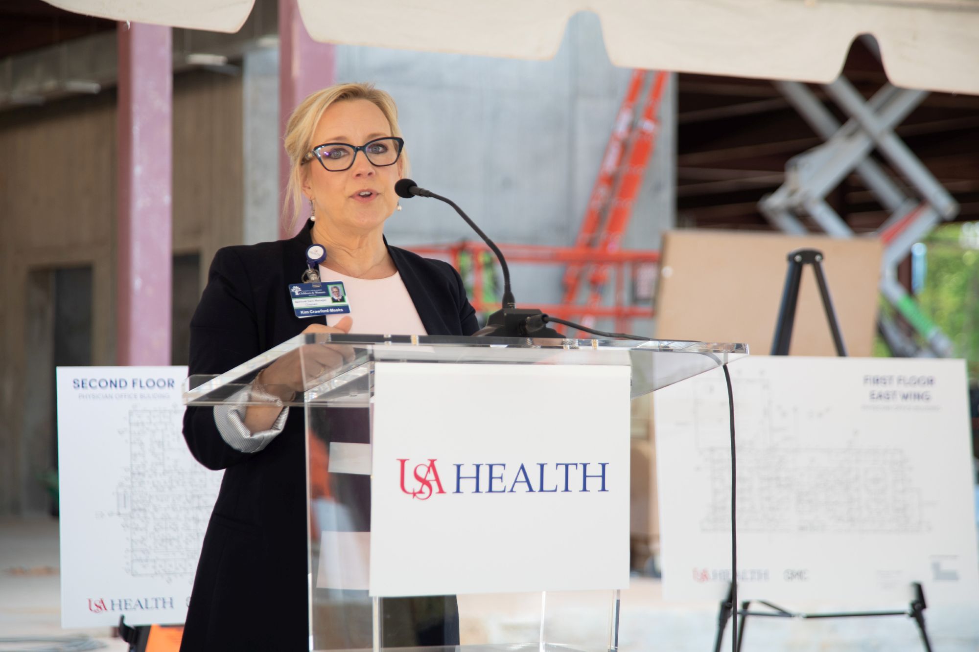 A man wearing a suit talking to a woman wearing a suit at a conference table.